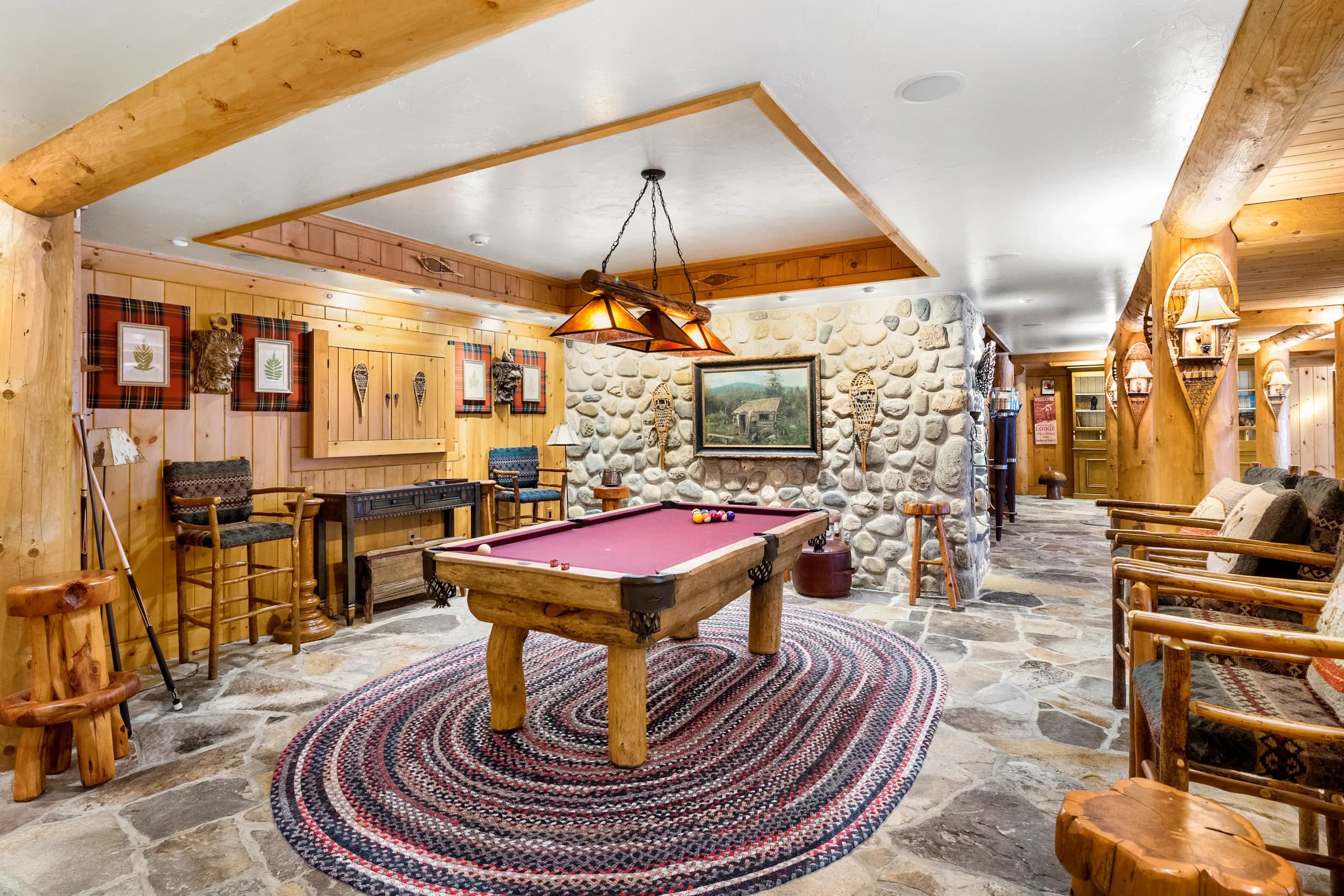 The stone-walled billiard room, burgundy felt glowing under a timber-and-mica light
