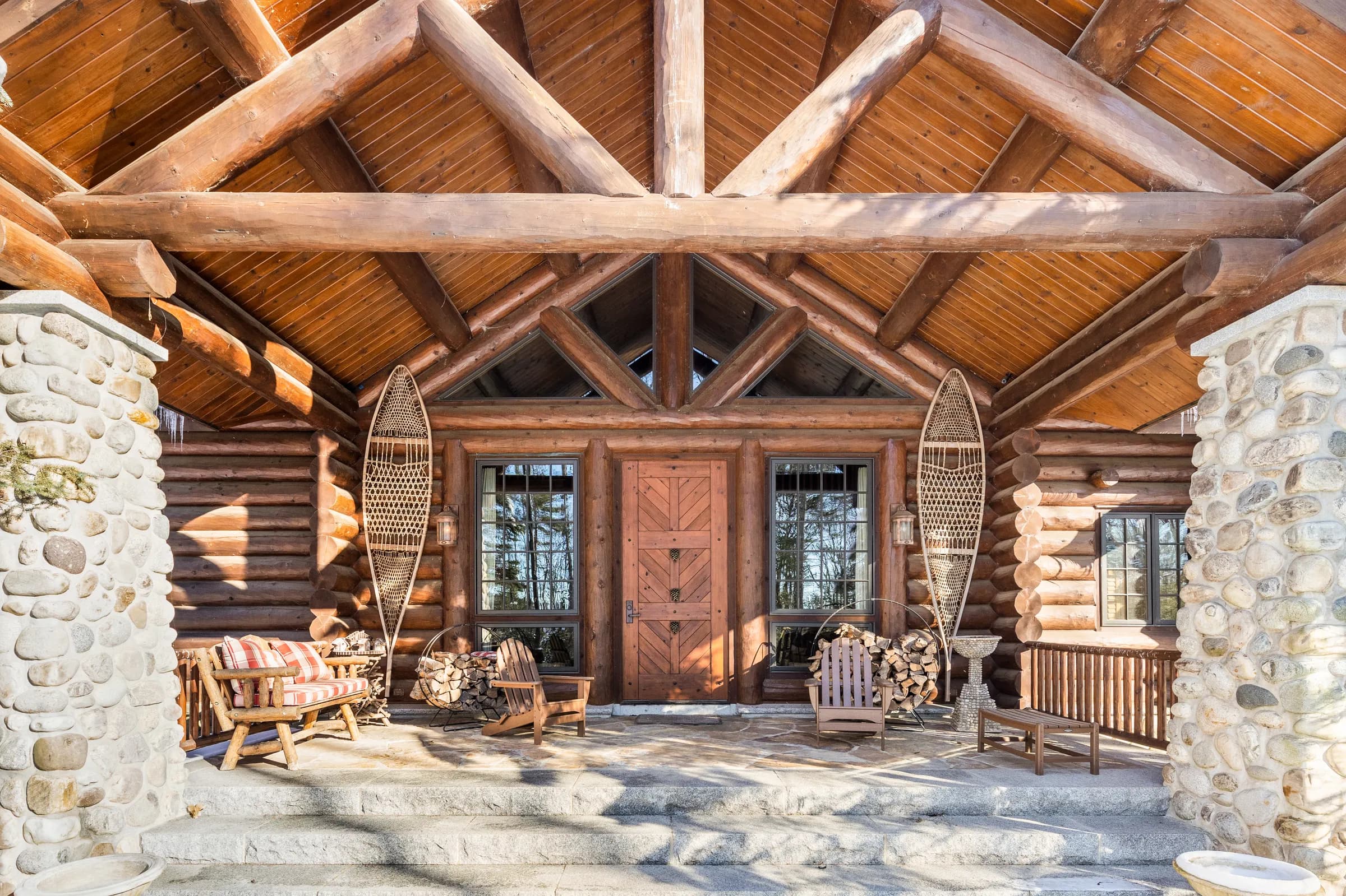 The grand log-truss entry portico of The Lodge, hung with bench swings, in fresh snow
