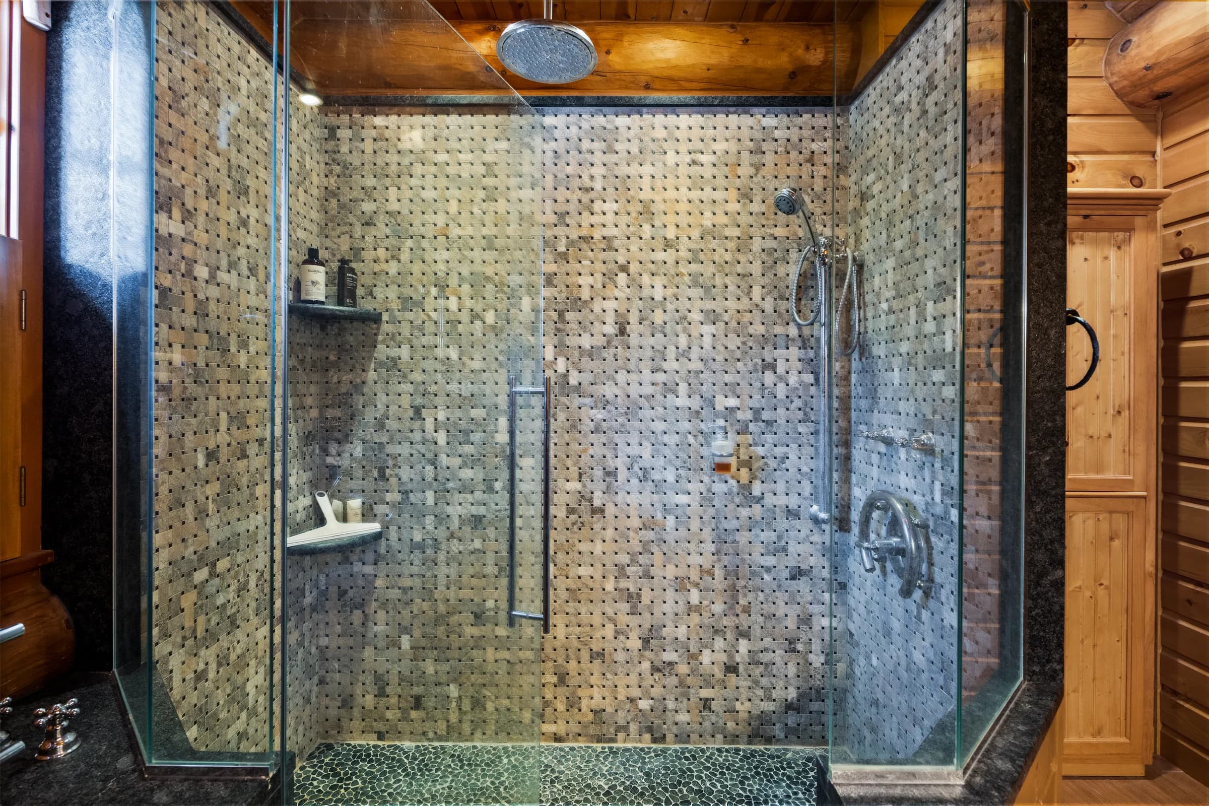 A floor-to-ceiling mosaic-tiled walk-in shower