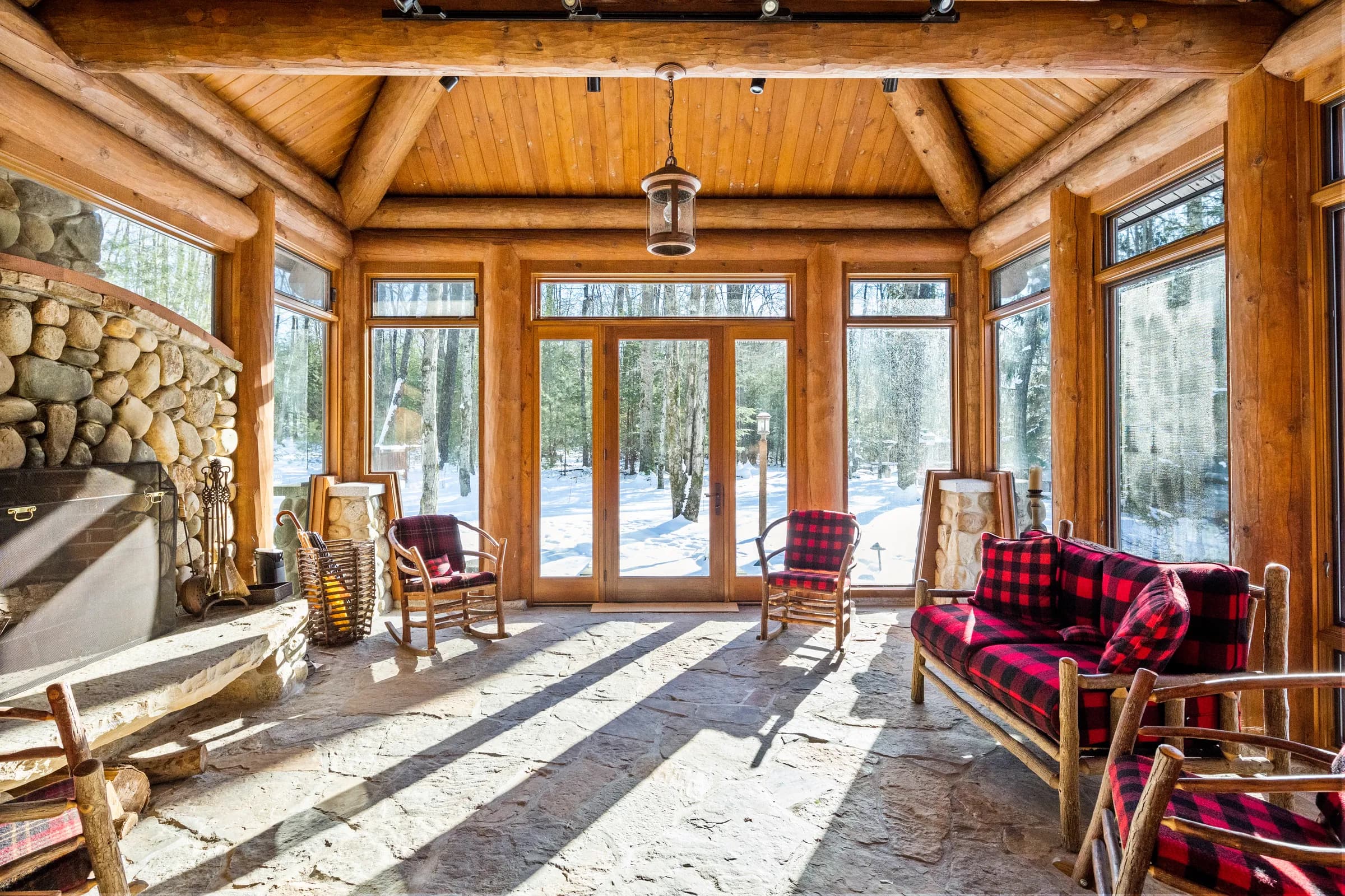 The glass-walled sunroom porch warmed by its own stone fireplace