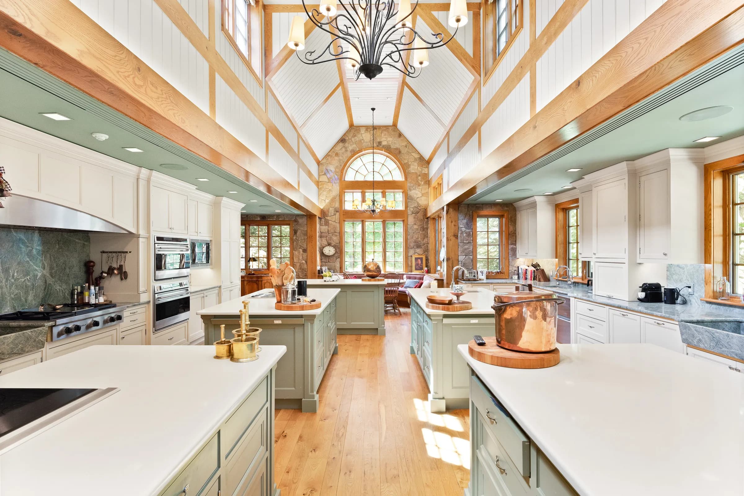 The five-island kitchen beneath its cathedral ceiling and arched stone window