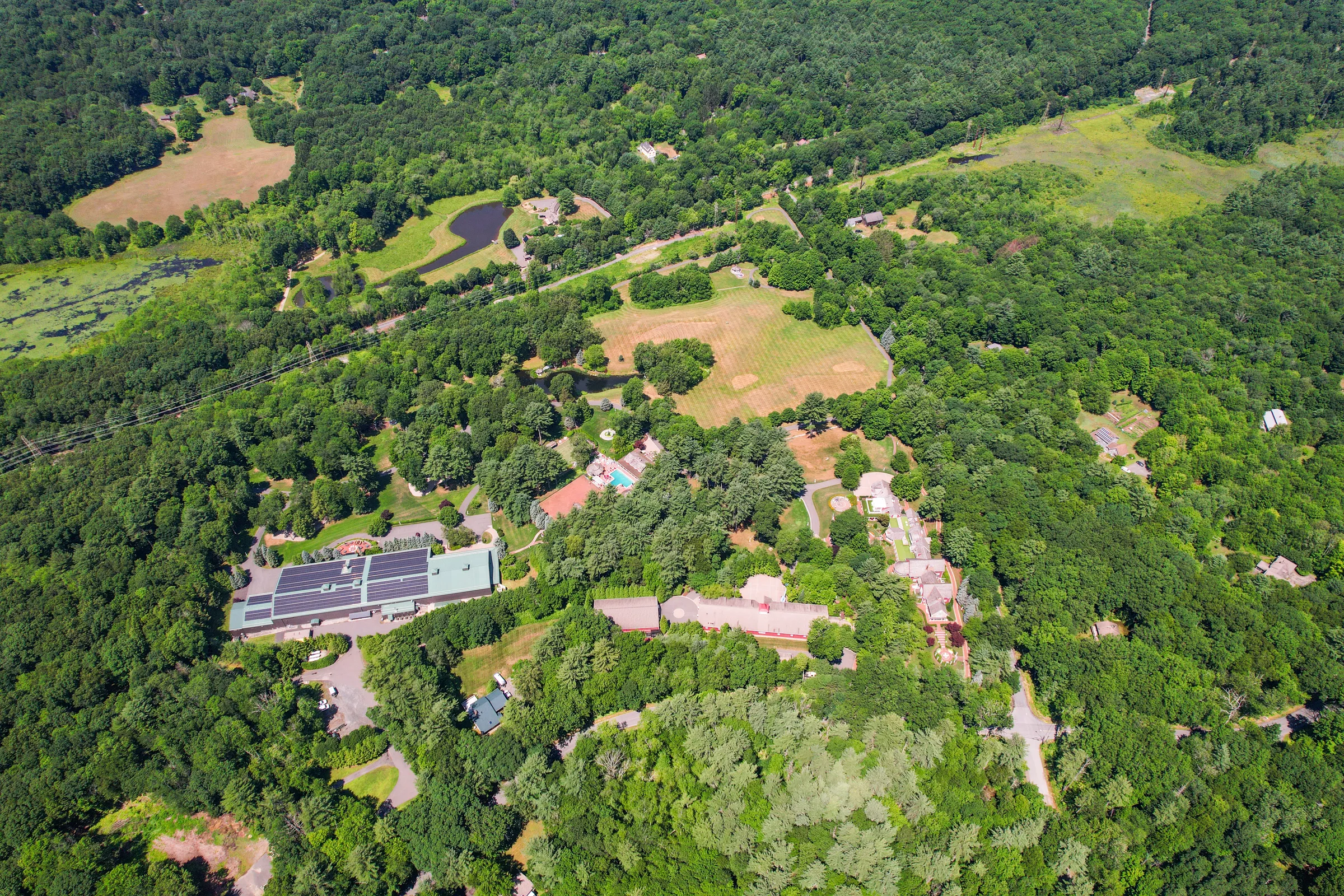 Aerial view of the Juggler Meadow compound surrounded by forest and farmland in the Leverett valley